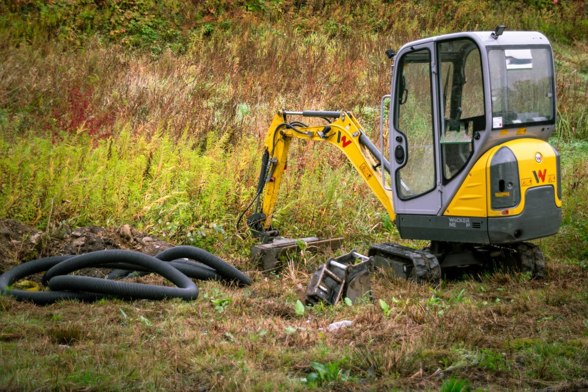 Compact excavator working in a grassy field